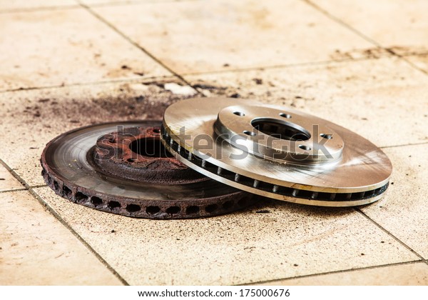 Auto in service.\
New and old front brake disks for modern car lying on floor in\
mechanic garage car\
service.