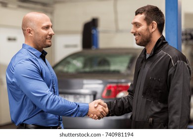 Auto Service, Repair, Deal And People Concept - Mechanic And Customer Or Car Owner Shaking Hands At Workshop