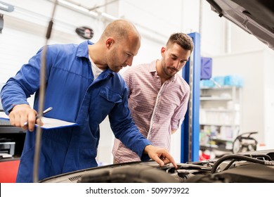 Auto Service, Repair, Maintenance And People Concept - Mechanic With Clipboard And Man Or Owner Looking At Broken Car Engine At Shop