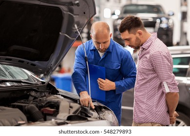 Auto Service, Repair, Maintenance And People Concept - Mechanic With Clipboard And Man Or Owner Looking At Broken Car Engine At Shop