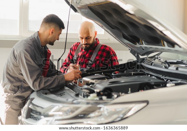 auto service,\
repair, maintenance and people concept - mechanic men with wrench\
repairing car engine at\
workshop