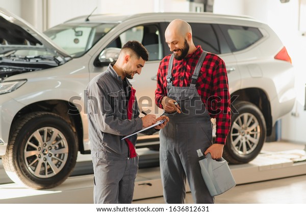 auto service,\
repair, maintenance and people concept - mechanic men with wrench\
repairing car engine at\
workshop