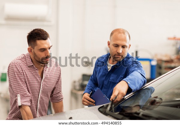 auto\
service, repair, maintenance and people concept - mechanic checking\
windshield wiper and man or owner at car\
shop