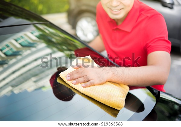 Auto service staff\
cleaning car rear windshield with microfiber cloth - car detailing\
and valeting concept