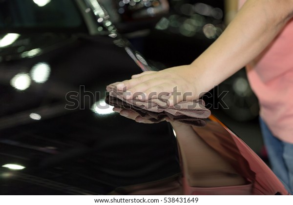 Auto service staff cleaning car with\
microfiber cloth - car detailing and valeting concept. Hand with\
microfiber cloth polishing car. Select\
focus.