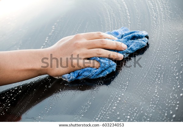 Auto service\
staff cleaning car rear\
windshield