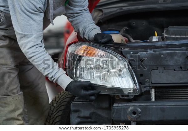 Auto service. Technician\
assembling an automobile headlight lamp. bodywork repair for\
insurance