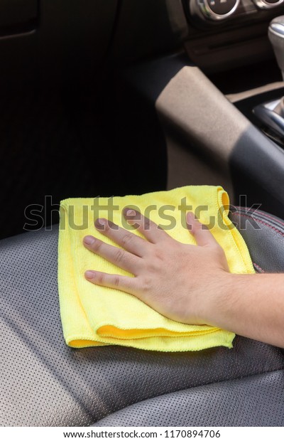 Auto service worker cleaning inside car with micro\
fiber cloth
