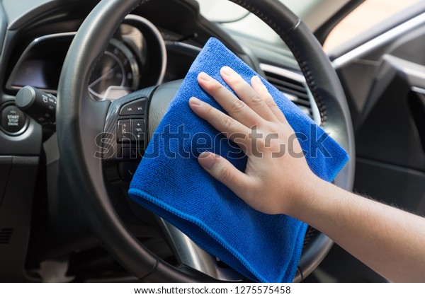Auto service worker cleaning inside car with micro\
fiber cloth