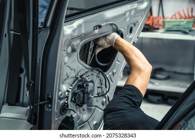 Auto service worker disassembles car door for repair, restoration, tuning car sound or installing noise insulation or soundproofing
