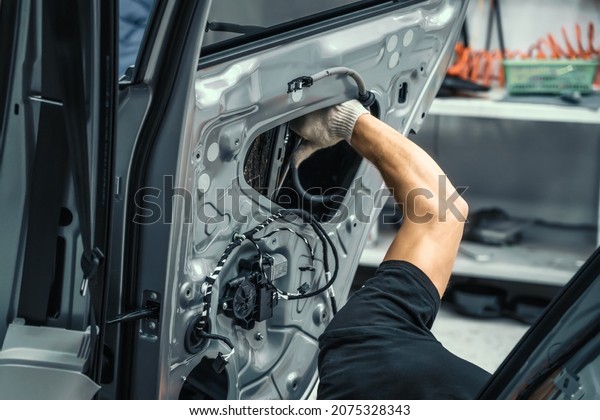 Auto service worker disassembles car door\
for repair, restoration, tuning car sound or installing noise\
insulation or\
soundproofing