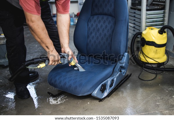 An\
auto service worker prepares and cleans the car\
seat