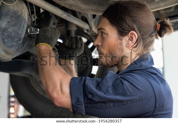 Auto services and Small\
business concepts. Auto mechanic hands using wrench to repair a car\
engine.