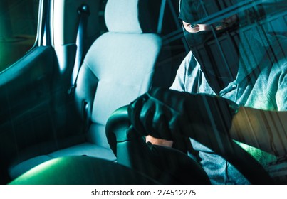 Auto Theft Carjacking. Young Caucasian Male Carjacker In Black Mask Driving Stolen Car. Motor Vehicle Theft Concept Photography. Grand Auto Theft.