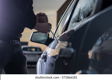 Auto Thief In Black Balaclava Trying To Break Into Car With Screwdriver. Car Thief, Car Theft