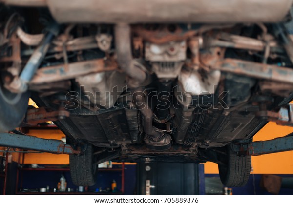 Auto view from the bottom. Garage mechanic raised\
the car on the lift.