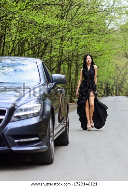 Auto and woman traveler. Trip and wanderlust. Hiking\
solo. Vehicle selective focus. Sexy woman go along road in fashion\
dress. Travelling and wanderlust. Pretty girl travel on foot.\
Travel by car.