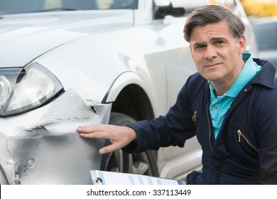 Auto Workshop Mechanic Inspecting Damage To Car And Filling In Repair Estimate