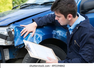 Auto Workshop Mechanic Inspecting Damage To Car And Filling In Repair Estimate