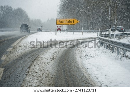 An autobahn exit ramp is covered in brown slush and packed snow. The word Ausfahrt is visible on the roadway, guiding drivers through messy winter conditions toward the exit.
