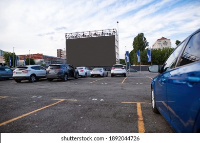 Autocinema parking with cars watching big screen during day session. Free time, leisure and entertainment concept