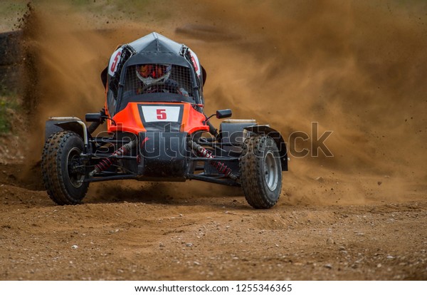 Autocross on a dusty road. Car in competition up the\
road on a dirt road