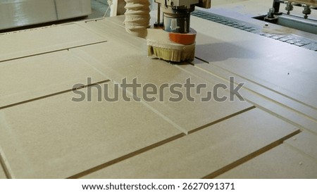Automated cnc machine cutting precise grooves into particle board, creating separate components