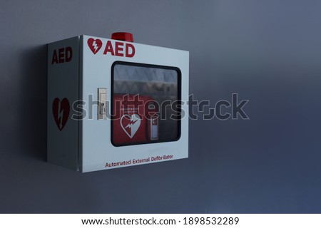 Automated External Defibrillator (AED) in white box on the wall.Heart defibrillator on gray background.