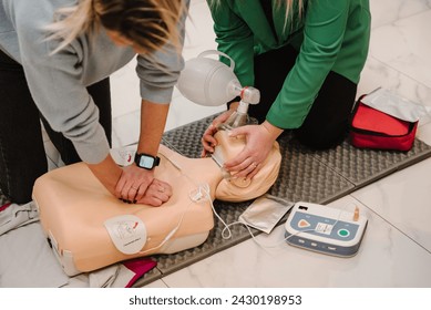 Automated external defibrillator device, AED with training dummy mannequin. Use an automatic defibrillator in conducting basic cardiopulmonary resuscitation of victim. Demonstrating chest compressions - Powered by Shutterstock