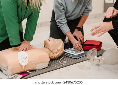 Automated external defibrillator device, AED with training dummy mannequin. Use an automatic defibrillator in conducting basic cardiopulmonary resuscitation of victim. Demonstrating chest compressions