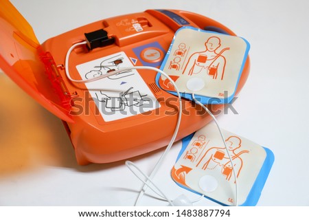 Automated External Defibrillator with pads on display. It is a portable electronic device that automatically diagnoses the life-threatening cardiac arrhythmias.
