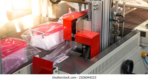 Automated food packing machine. Food container flow wrapping machine. Food packaging machine in production line of food industry.