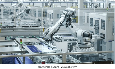 Automated Manufacturing Facility. White Industrial Robot Arm at Production Line at Modern Bright Factory. Solar Panels are being Assembled on Conveyor. - Powered by Shutterstock