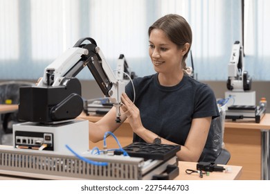 Automated manufacturing industries. Innovative technology. Female engineer working with compact desktop robotic arm for for manufacturing lines in workshop. Smart automation tasks concept - Powered by Shutterstock