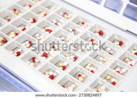 Automated medication dispensing machine with sorted tablets and capsules in a pharmacy tray.