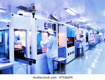 Automated production line in modern Solar silicon factory. Slow shutter speed with figures in motion.
