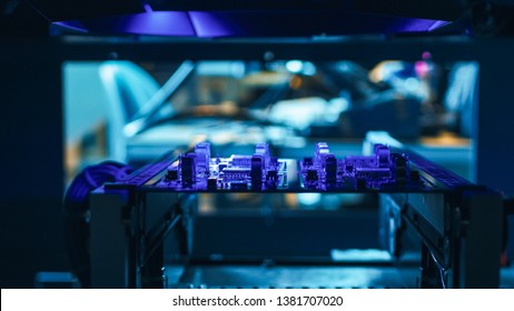 Automated Robotic Industrial Equipment is Testing Electronic Printed Circuit Board with Purpule Neon Light and Laser Technology After Assembly.