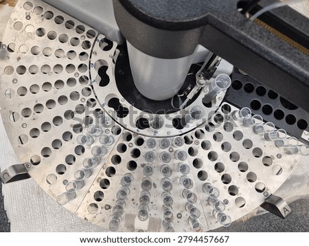 An automated sample analyzer prepares to process a batch of water quality samples arranged in a circular carousel. The organized test tubes and precision instrument highlight the technology used to support environmental monitoring, compliance testing, and analytical measurement.