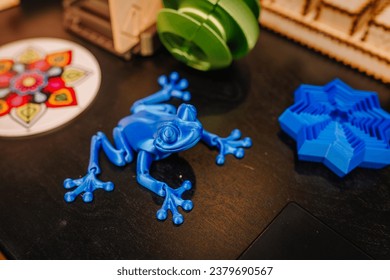 Automatic 3D printer machine printing plastic model of blue frog toy at modern technology exhibition. 3D printing, additive technologies, 4.0 industrial revolution and futuristic concept
