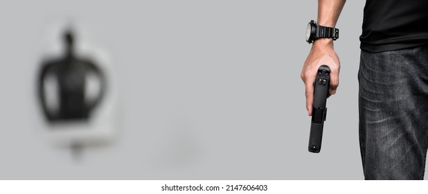 Automatic 9mm pistol gun holding in right hand of shooter in front of blurred man-target shooting paper, concept for training to shoot guns for custody and crime prevention
