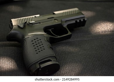 Automatic 9mm pistol gun on black leather background, soft and selective focus.