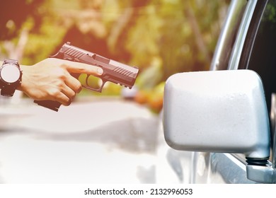 automatic 9mm pistol holding in hand of gun shooter and aming to the glassdoor of the car, concept for car robbery and vip protection, soft and selective focus.
