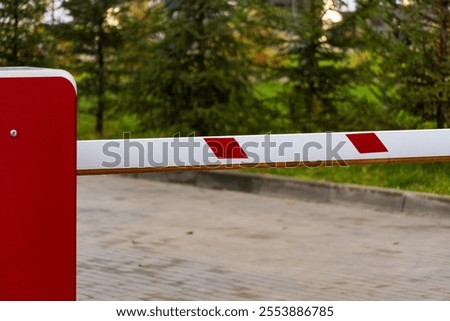 The automatic barrier gate is closed, managing vehicle access to the parking lot. The setup ensures safety and control of entry points while maintaining a clear boundary.