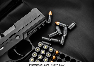 Automatic black 9mm pistol and bullets on black leather background, selective and soft focus.