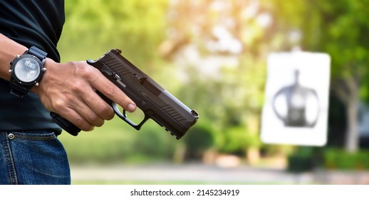 Automatic black 9mm pistol gun holding in right hand of shooter and ready to aim to the man-target shooting paper ahead, concept for training and practising human to be body guard and vip protectors.