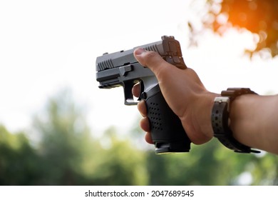 Automatic black 9mm pistol holding in hands aming to the shooting tar. concept for sports, recreations, bodyguard, and security training around the world. Selective and soft focus.