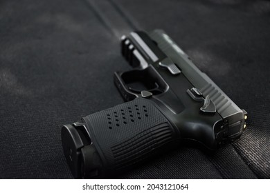 Automatic black 9mm pistol on black leather table. Soft and selective focus specific on gun.