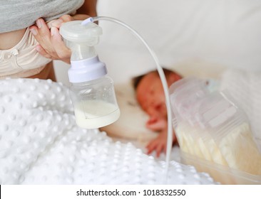 Automatic breast pump. Mothers breasts milk for newborn baby in bed room at home.
