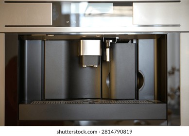 Automatic built-in coffee machine interior showing brewing unit dispenser nozzle mechanism component appliance technology stainless steel kitchen equipment espresso system closeup with modern household design