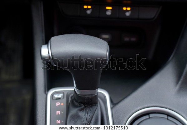 Automatic car gear with leather details and chrome\
elements with selective focus and blurred lighting buttons on\
background. Car interior with new gear stick. Automobile\
transmission gearshift\
